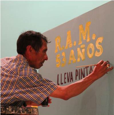 
						Arnulfo Herrada, escritura a mano con pincel. Muestra caligráfica con un trazo a pincel y boceto previo a lápiz. Los trazos gruesos y las terminaciones de las líneas de texto en amarillo se logran al repasar la pared dos o tres veces con la pintura. Cartagena, Colombia, 2010.
					