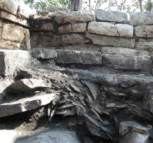 
						Restos de material quemado y fragmentos de cerámica en el interior de la cámara del baño de vapor de El Higo.
					
